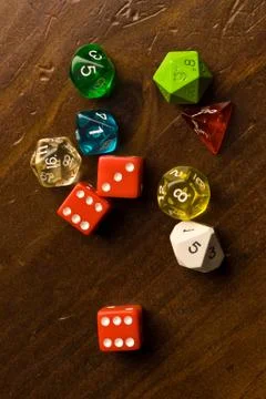 Multi-colored role play dice sitting on a wooden table top Stock Photos