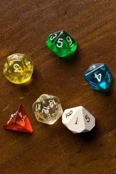 Multi-colored role play dice sitting on a wooden table top Stock Photos