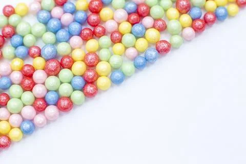 Multi-colored round glossy balls of sugar confectionery lie diagonally to the Stock Photos