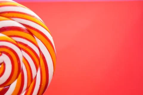 Multi-colored round lollipop on a bright red background. Close up. Stock Photos