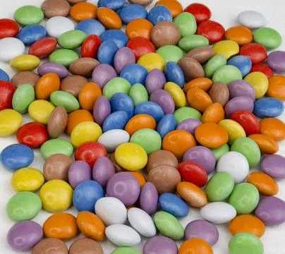 Multi-colored round small candies lie on the table. Stock Photos
