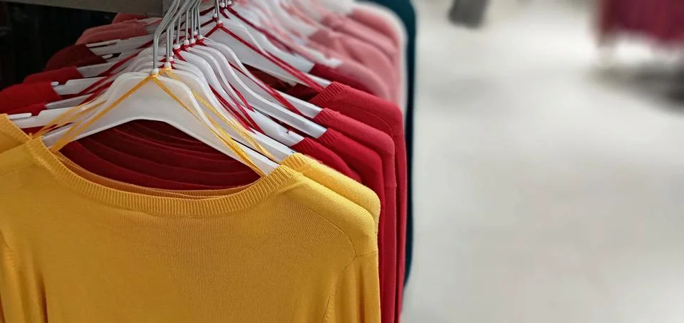 Multi-colored row of clothes hanging on hangers Stock Photos