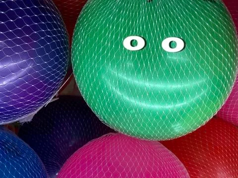 Multi-colored rubber balls in a grid. Balls show a face with a smile. Concept Stock Photos