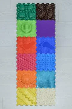 A multi-colored rubber puzzle mat lies on the floor. Orthopedic mat Stock Photos