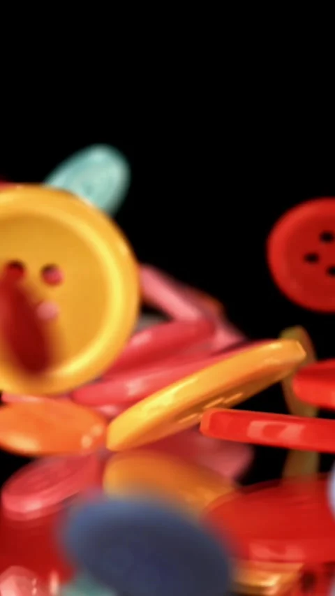 Multi-colored sewing buttons fall on the table. Filmed on a high-speed camera at Stock Footage 335367114