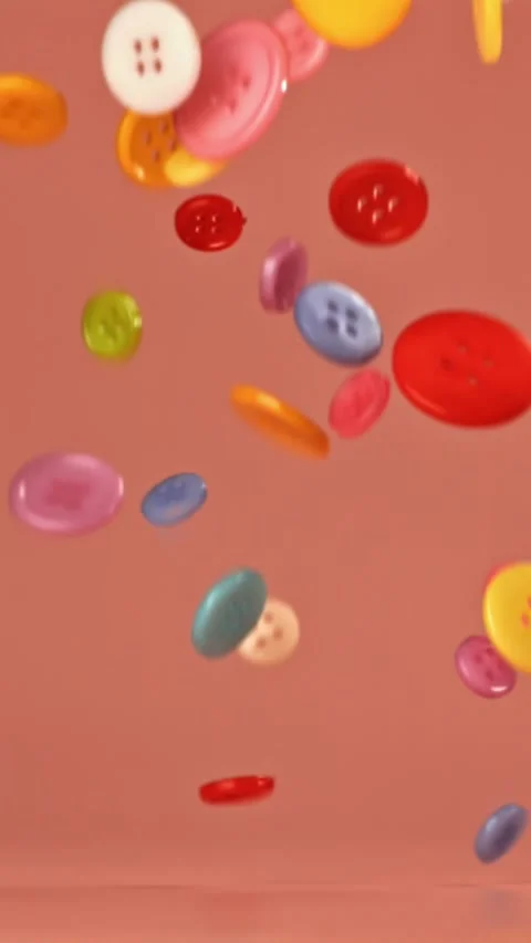 Multi-colored sewing buttons fall on a red table. Filmed on a high-speed camera Stock Footage 335367443