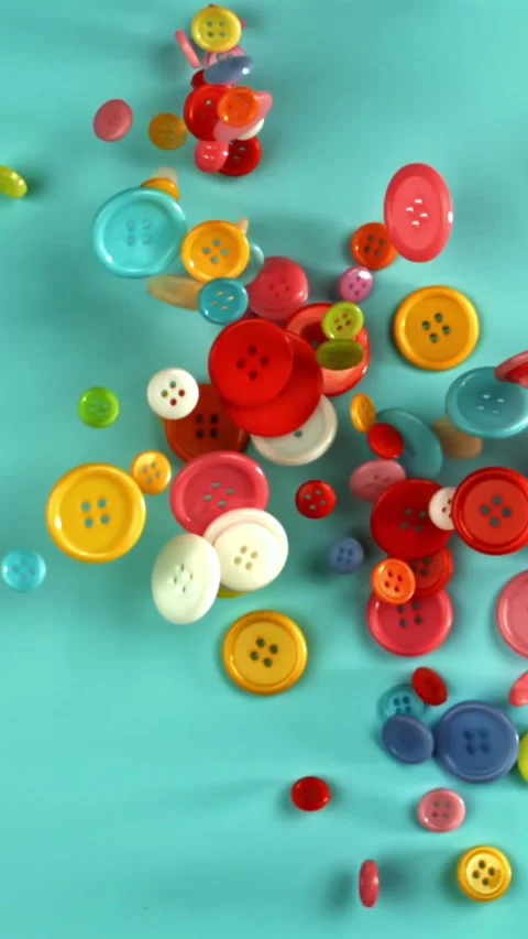 Multi-colored sewing buttons fall on the table. Filmed on a high-speed camera at Stock Footage 335368412