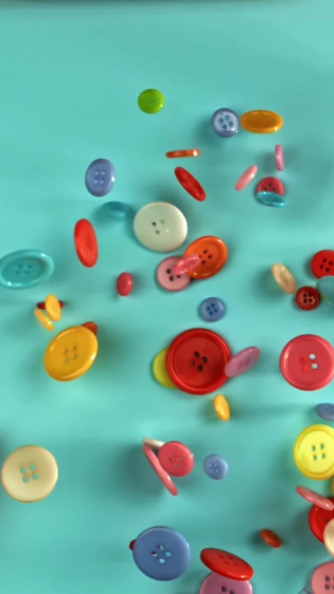 Multi-colored sewing buttons fall on the table. Filmed on a high-speed camera at Stock Footage 335368475