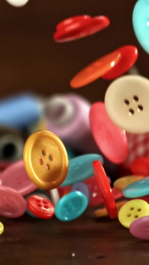 Multi-colored sewing buttons fall on the table. Filmed on a high-speed camera at Stock Footage 335372083