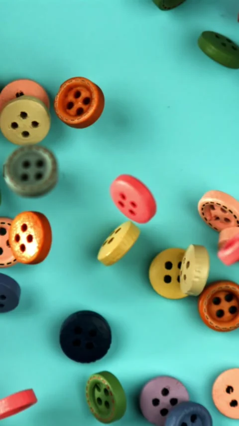 Multi-colored sewing buttons fall on the table. Filmed on a high-speed camera at Stock Footage 335377784