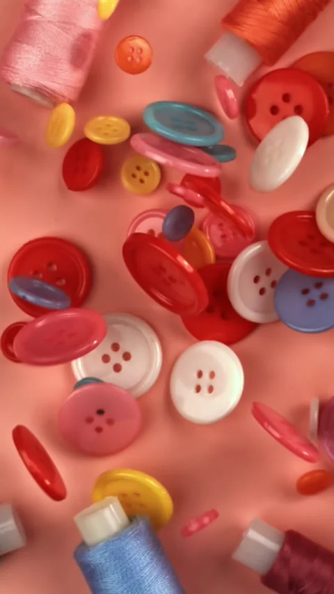 Multi-colored sewing buttons fall on a red table. Filmed on a high-speed camera Stock Footage 335378539