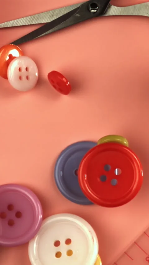 Multi-colored sewing buttons fall on a red table. Filmed on a high-speed camera Stock Footage 335380349