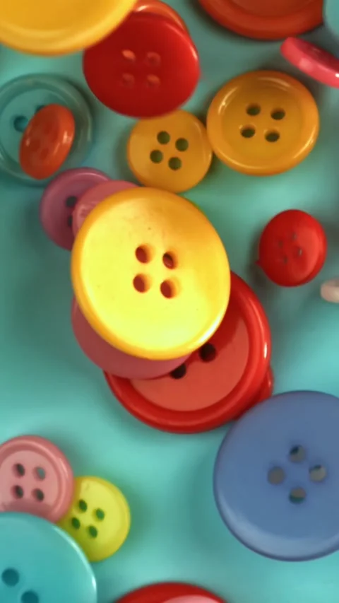 Multi-colored sewing buttons fall on the table. Filmed on a high-speed camera at Stock Footage 335381491
