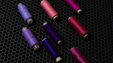 Multi-colored sewing threads diagonally against a dark background from above Foto stock