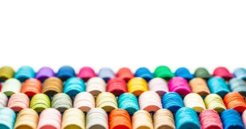Multi-colored sewing threads laid out in a row. Bright background. Stock Photos