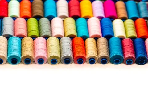 Multi-colored sewing threads laid out in a row. Bright background. Stock Photos