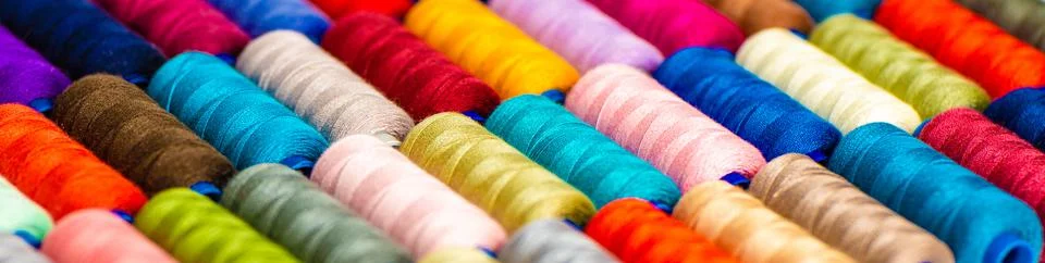 Multi-colored sewing threads laid out in a row. Bright background. Stock Photos