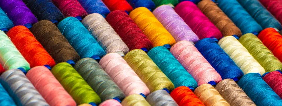 Multi-colored sewing threads laid out in a row. Bright background. Stock Photos