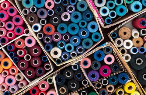 Multi-colored sewing threads laid out in a row. Bright background. Stock Photos