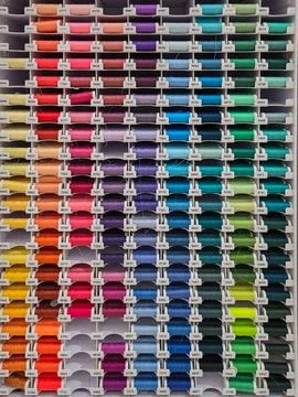 Multi-colored sewing threads on shop window. Hobby and needlework shop with coll Stockfoto's