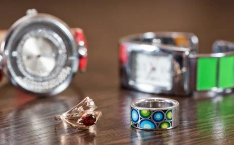 Multi-colored silver ring and a gold ring with a ruby on a background of watc 스톡 사진
