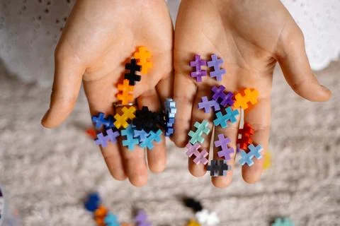 A multi-colored small puzzle set in a womans hands Stock Photos
