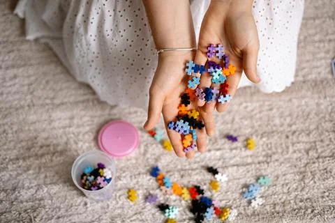 A multi-colored small puzzle set in a womans hands Stock Photos