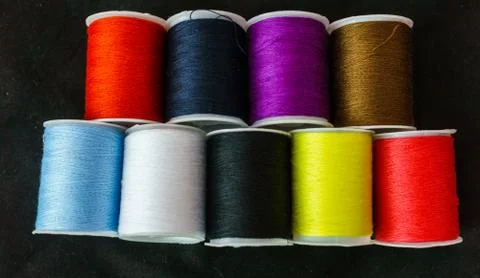 Multi-colored spools of thread close-up on a dark background. Stock Photos