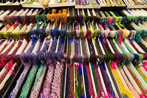 Multi-colored stone strands hang in grouped bundles on a tiered table, thei.. Stock Photos