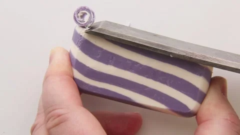 A multi-colored, striped piece of soap is cut smoothly. Stock Footage 310565101