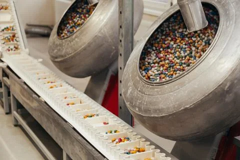 Multi-colored sugar candies spin in a drum at a confectionery industrial candy Stock Photos