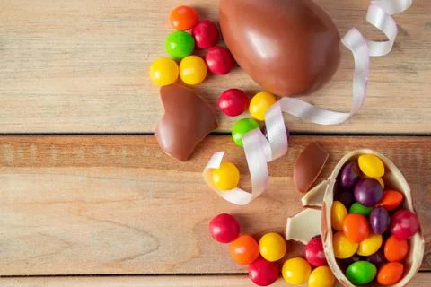 Multi-colored sweets and Easter chocolate eggs on a light wooden background. Stock Photos