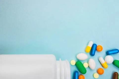 Multi-colored tablets and capsules, white bottle for tablets, pharmaceutical  Stock Photos