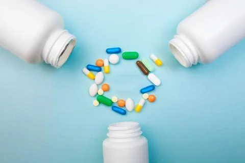 Multi-colored tablets and capsules, white bottle for tablets, pharmaceutical  Stock Photos