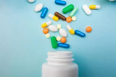 Multi-colored tablets and capsules, white bottle for tablets, pharmaceutical  Stock Photos