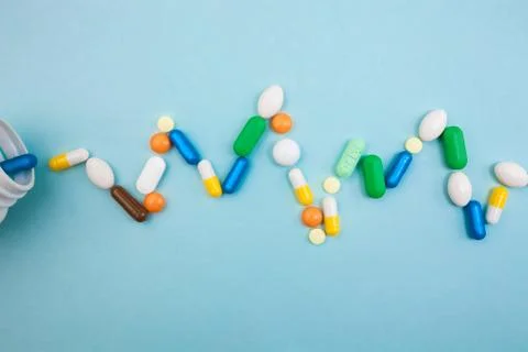 Multi-colored tablets and capsules in pulsation heartbeat white bottle for ta Stock Photos