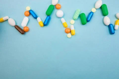 Multi-colored tablets and capsules in pulsation heartbeat white bottle for ta Stock Photos
