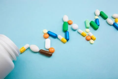 Multi-colored tablets and capsules in pulsation heartbeat white bottle for ta Stock Photos