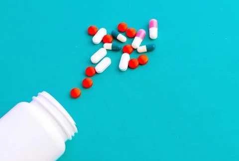 Multi-colored tablets and capsules, white bottle for tablets Stock Photos