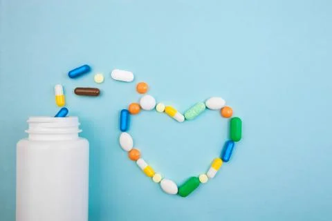 Multi-colored tablets and heart-shaped capsules, white bottle for tablets, ph Stock Photos