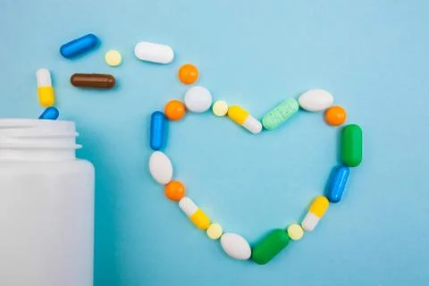 Multi-colored tablets and heart-shaped capsules, white bottle for tablets, ph Stock Photos