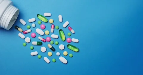 Multi-colored tablets spilling out of open bottle on to surface 動画素材 303240542