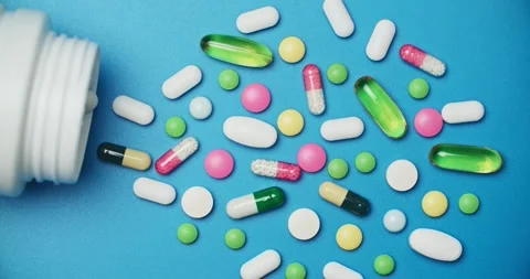 Multi-colored tablets spilling out of open bottle on to surface 動画素材 303240558