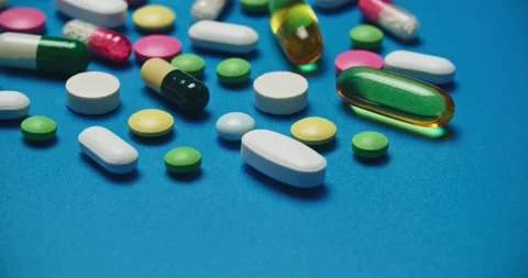 Multi-colored tablets spilling out of open bottle on to surface Vídeos de archivo 303240570