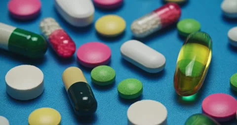 Multi-colored tablets spilling out of open bottle on to surface Vídeo Stock 303240646