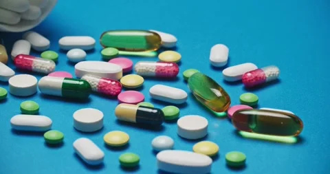 Multi-colored tablets spilling out of open bottle on to surface Vídeo Stock 303241155
