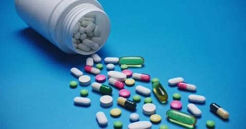 Multi-colored tablets spilling out of open bottle on to surface 스톡 동영상 303241160