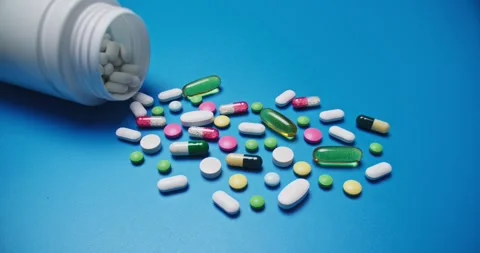 Multi-colored tablets spilling out of open bottle on to surface 動画素材 303241428