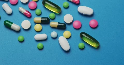 Multi-colored tablets spilling out of open bottle on to surface Vídeos de archivo 303241711