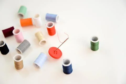 Multi colored thread spools, needle and red button Stock Photos